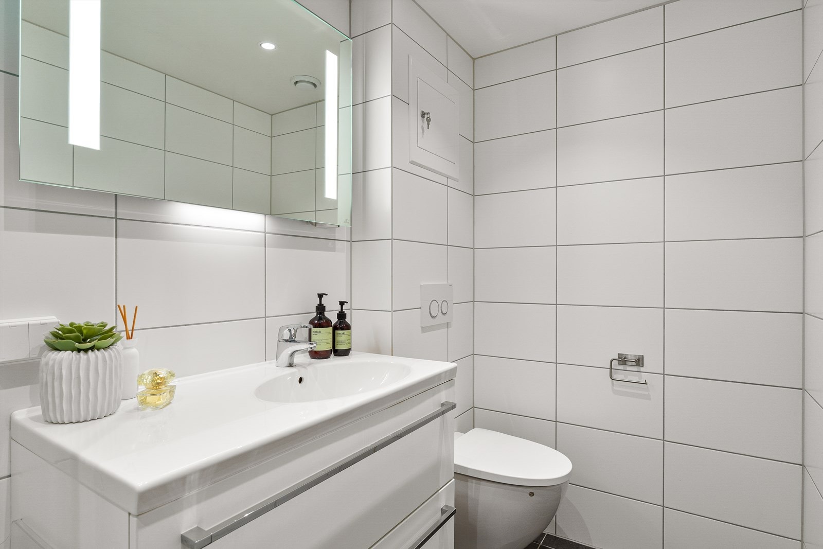 Badet er helfliset og har elektriske varmekabler i gulvet. Innredningen inkluderer servantseksjon og veggmontert toalett. Galleribilde