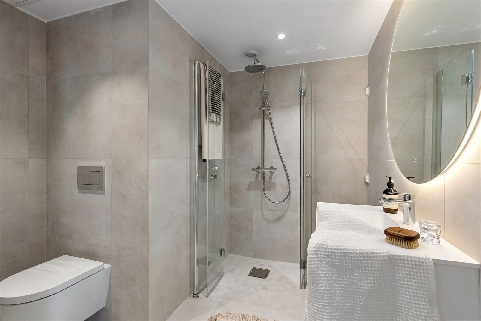 Badet er delikat flislagt og har vegghengte toalett, dusj i hjørnet og servant med flott innredning. Galleribilde