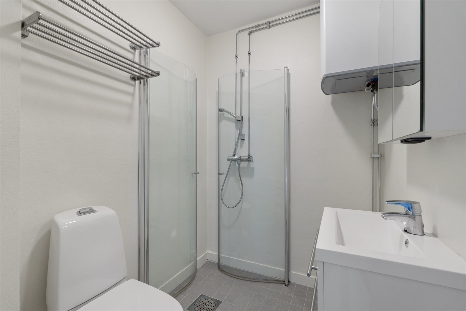 Badet er pent innredet med dusjhjørne, servant og toalett Galleribilde