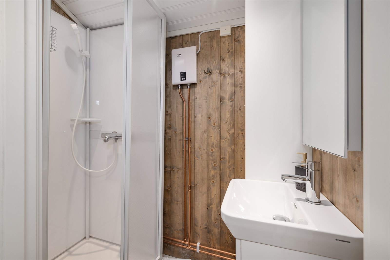 Det ble etablert rom med dusjkabinett i 2022, utstyrt med dusjkabinett og innredning m/servant. Badet har direkte vannvarmer fra Coax. (Rommet er ikke omsøkt kommunen og godkjent for varig opphold) Galleribilde