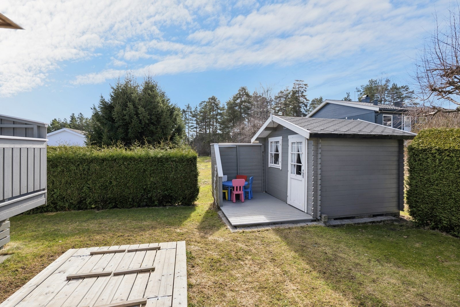Bakhagen er rammet inn av velholdt hekk - og de minste barna har en trygg oase her med sandkasse og lekestue Galleribilde