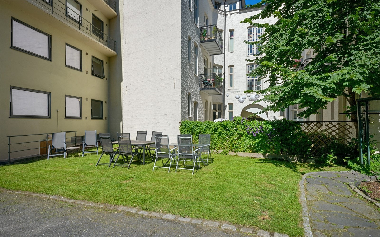 Pent opparbeidede fellesarealer med sittegrupper, plen og beplantning. Galleribilde