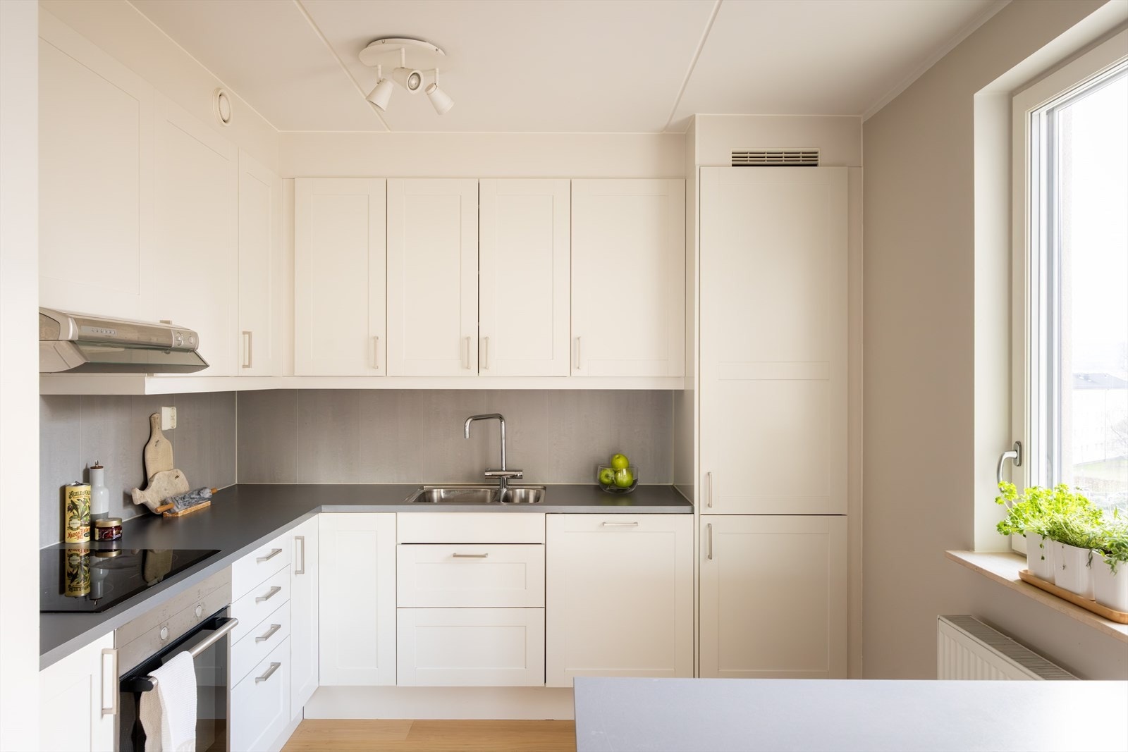 Kjøkkeninnredningen består av hvite, profilerte fronter og benkeplate av laminat med nedfelt vask- og skyllekum. Galleribilde