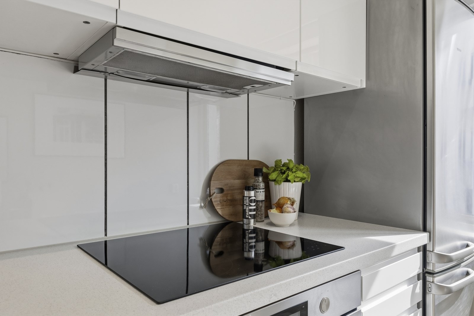 Hvitevarer bestående av induksjon koketopp, stekeovn, kjøl/frys og oppvaskmaskin. Ventilator over kokesone. Galleribilde