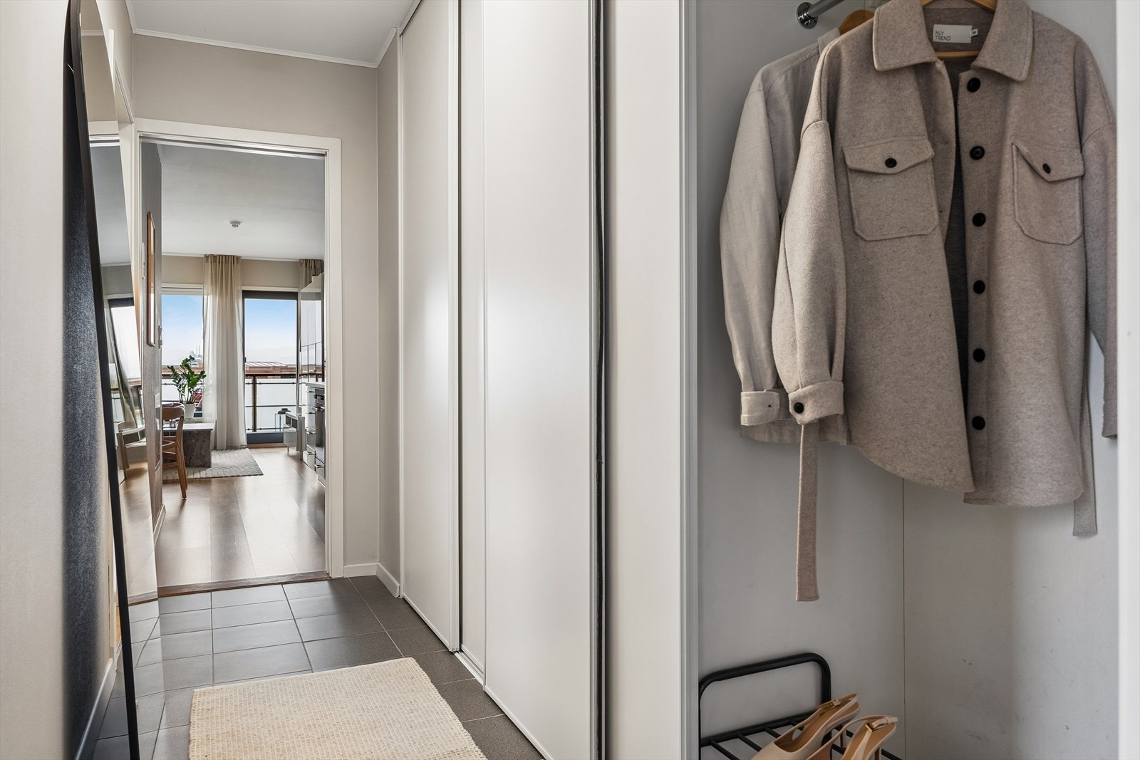 Her kommer man inn til en innbydende entré som utgjør hjemmets førsteinntrykk. Inngangspartiet er innredet med en praktisk skyvedørsgarderobe for yttertøy og sko. Galleribilde