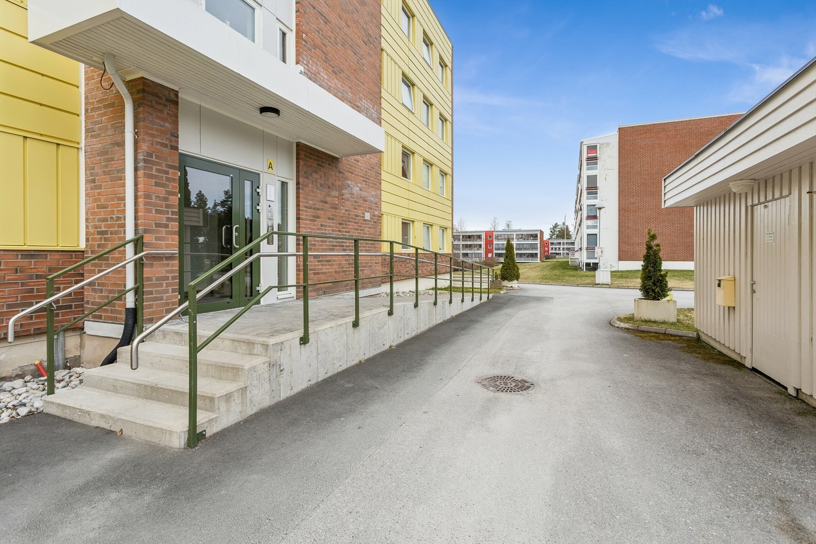 Enkel adkomst til inngangspartiet via asfaltert gangvei og rampe. Bod til høyre for felles sykkelparkering. Galleribilde