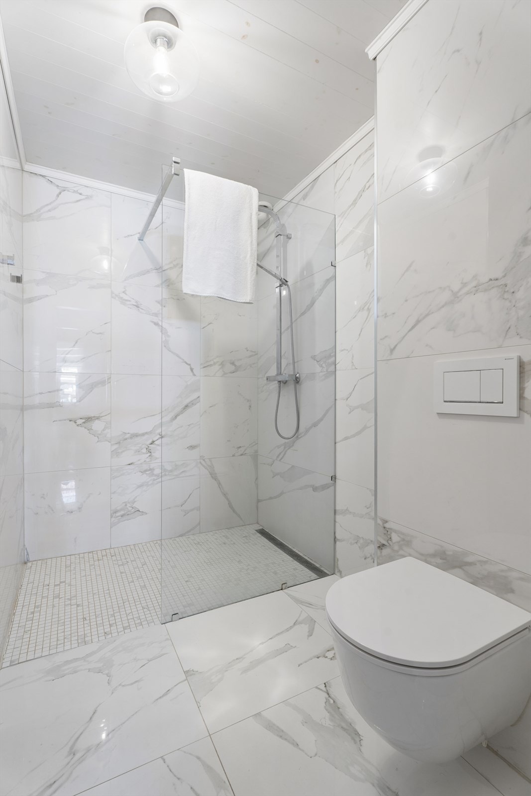 Badet har en romslig dusjnisje med glassdører og vegghengt toalett. Galleribilde