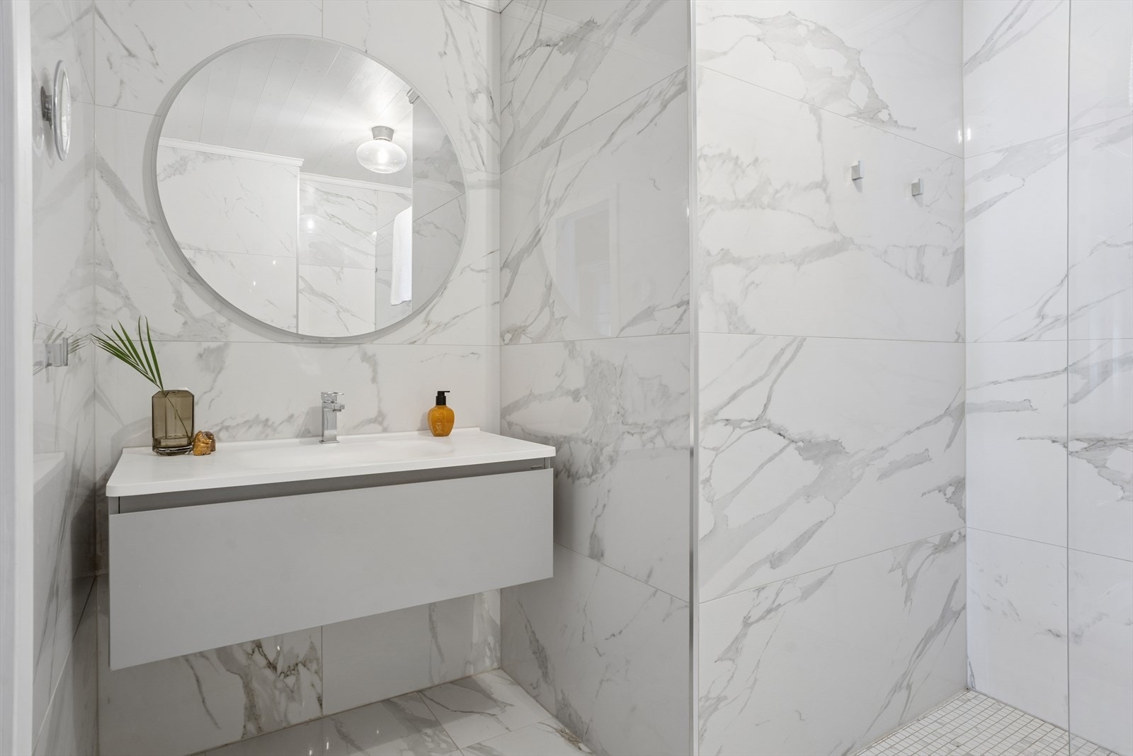 Hovedbadet er helfliset med store, marmor-inspirerte fliser og utstyrt med en moderne, vegghengt servantinnredning. Galleribilde