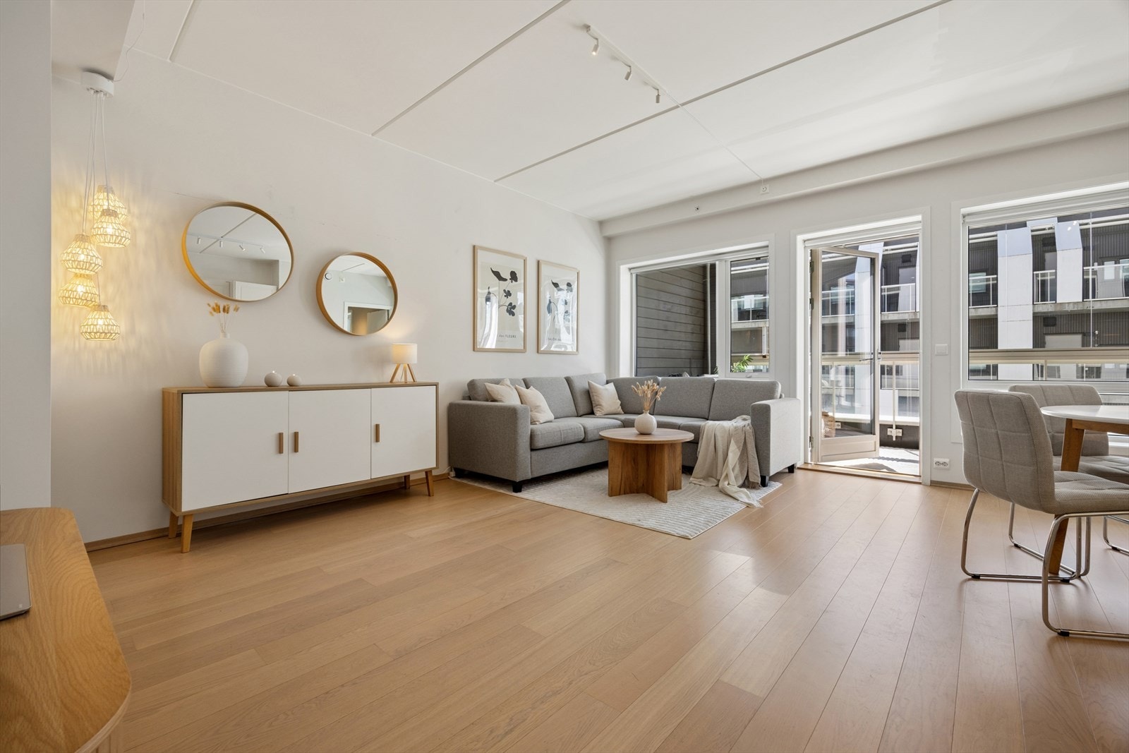 Et lyst og åpent oppholdsrom, innredet med parkett på gulv og lysmalte overflater. Galleribilde