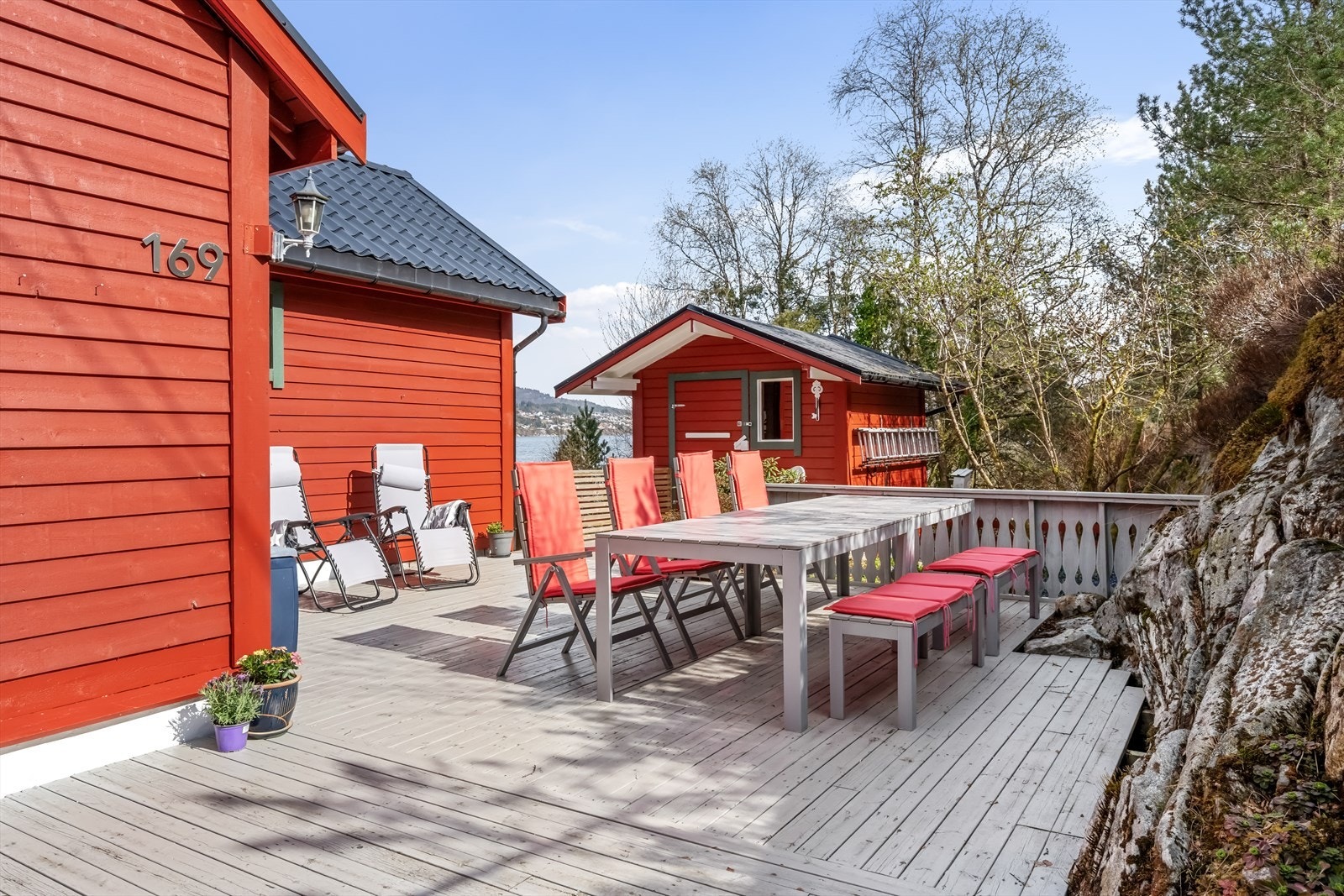 Uteareal ved inngangsparti hytte og anneks. Vedskjul i ende av bilde. Galleribilde