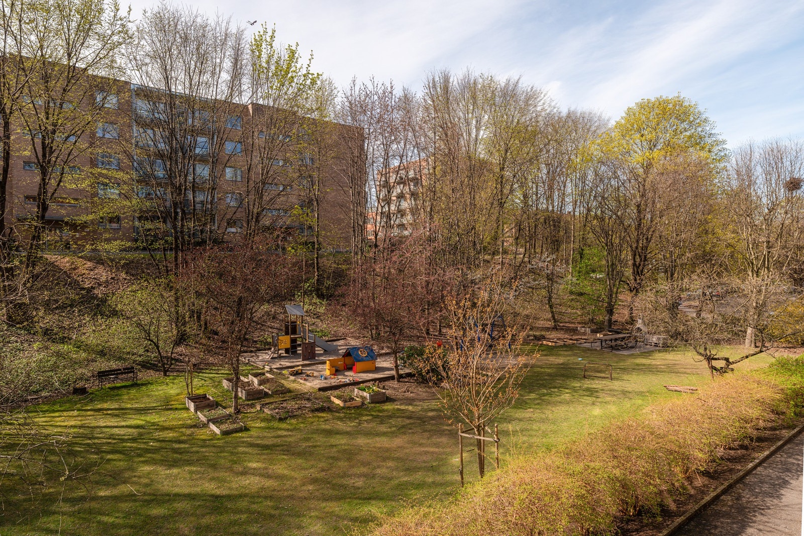 Balkongen vender ut mot fine og frodige fellesarealer som er opparbeidet med plen, grillplass, plantekasser og lekeplass for de minste beboerne. Galleribilde