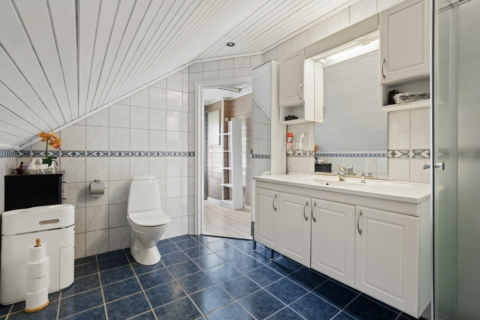 Badet på loftet har flislagt gulv med gulvvarme og er innredet med dusjkabinett og baderomsinnredning med servant. Galleribilde