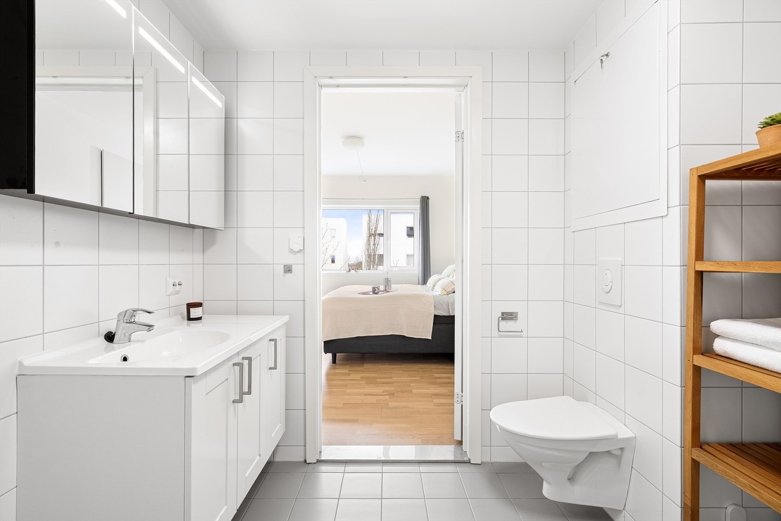 Badet er helfliset og har vegghengt toalett, dusjhjørne, hel servant, speil med belysning og god oppbevaringsplass i baderomsmøbel og speil. Galleribilde