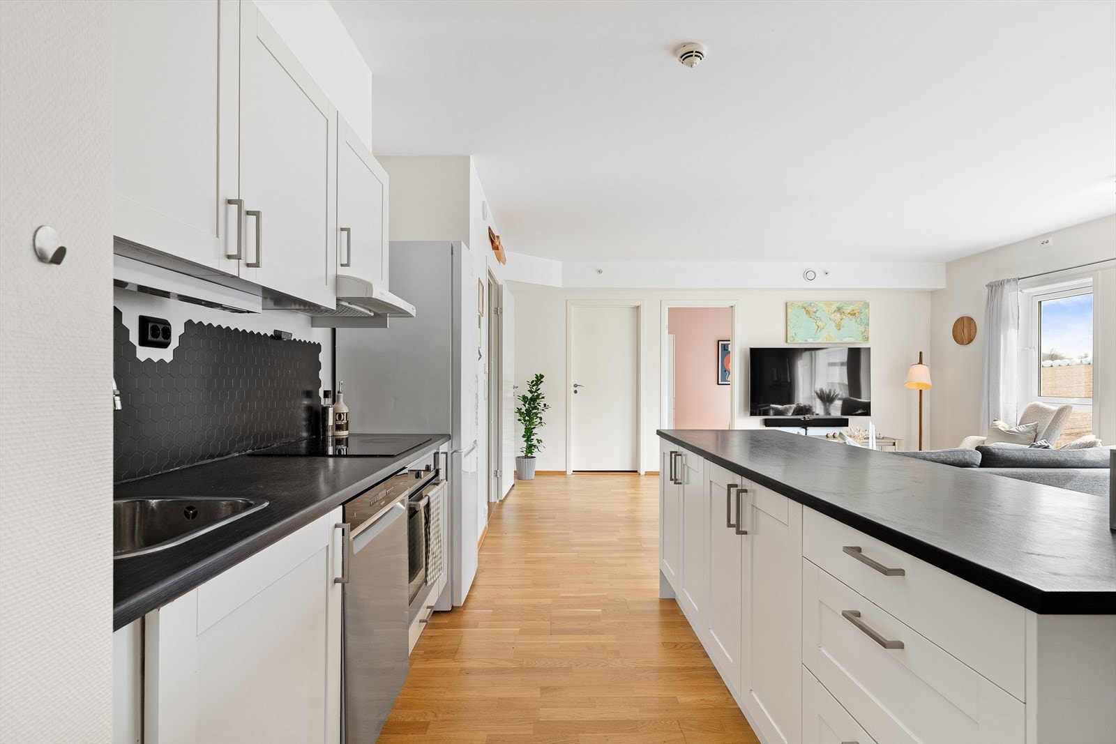 Kjøkken fra Norema med hvite, profilerte fronter og benkeplate av laminat. Her er det rikelig med skap- og benkplass. Galleribilde