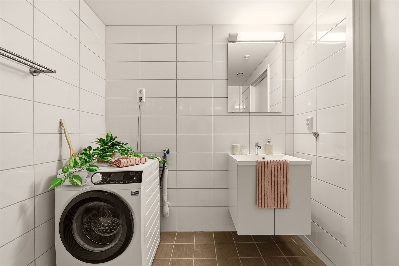 Dette badet inneholder servantmøblement med heldekkende servant, speil med vegglampe, vegghengt toalett, opplegg for vaskemaskin/tørketrommel og dusj med innfellbare dører i herdet glass. Galleribilde
