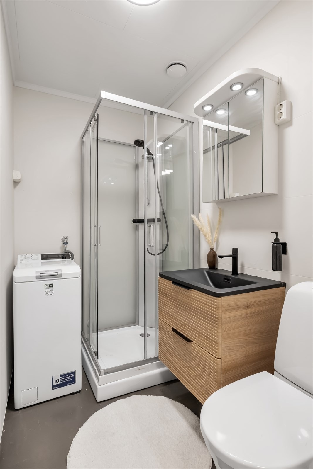 Baderommet er utstyrt med wc på sokkel, servantinnredning, dusjkabinett og opplegg for vaskemaskin. Det er malte plater i himling samt tapetserte vegger, og gulvet er belagt med belegg. Badet er fra byggeår. Galleribilde