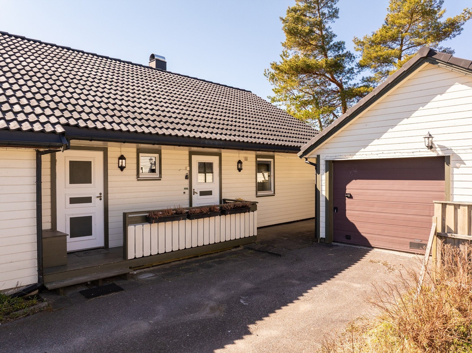 På inngangssiden er det sommerstid sol tidlig på dagen. Entrédøren til høyre, vaskerommets ytterdør til venstre. Galleribilde