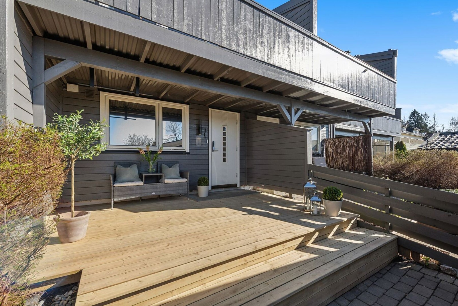 Inngangspartiet har en romslig uteplass med belegningsstein og en terrasse på 13 kvm. Her er det også nye terrassebord fra 2023, som er slipt i 2026. Galleribilde