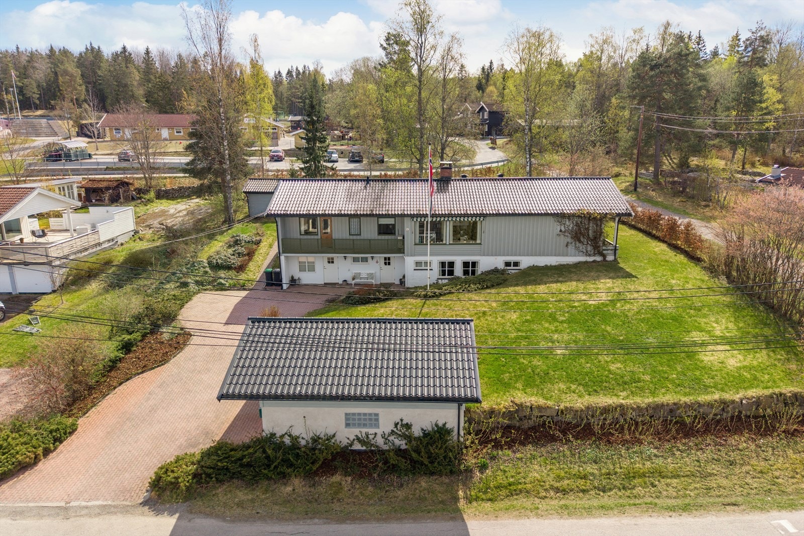 Eiendommen inkluderer en frittstående dobbelgarasje og en romslig, steinsatt gårdsplass. Galleribilde