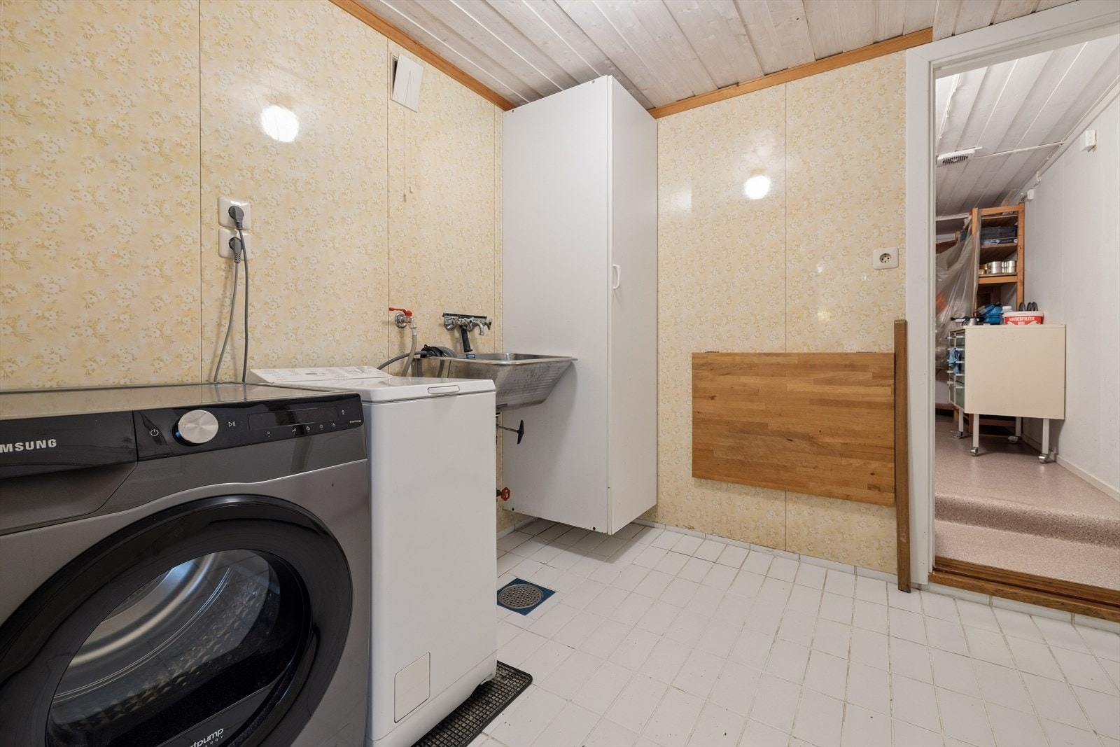 Praktisk vaskerom i sokkeletasjen med fliser på gulv, skyllekum og opplegg for vaskemaskin. Galleribilde