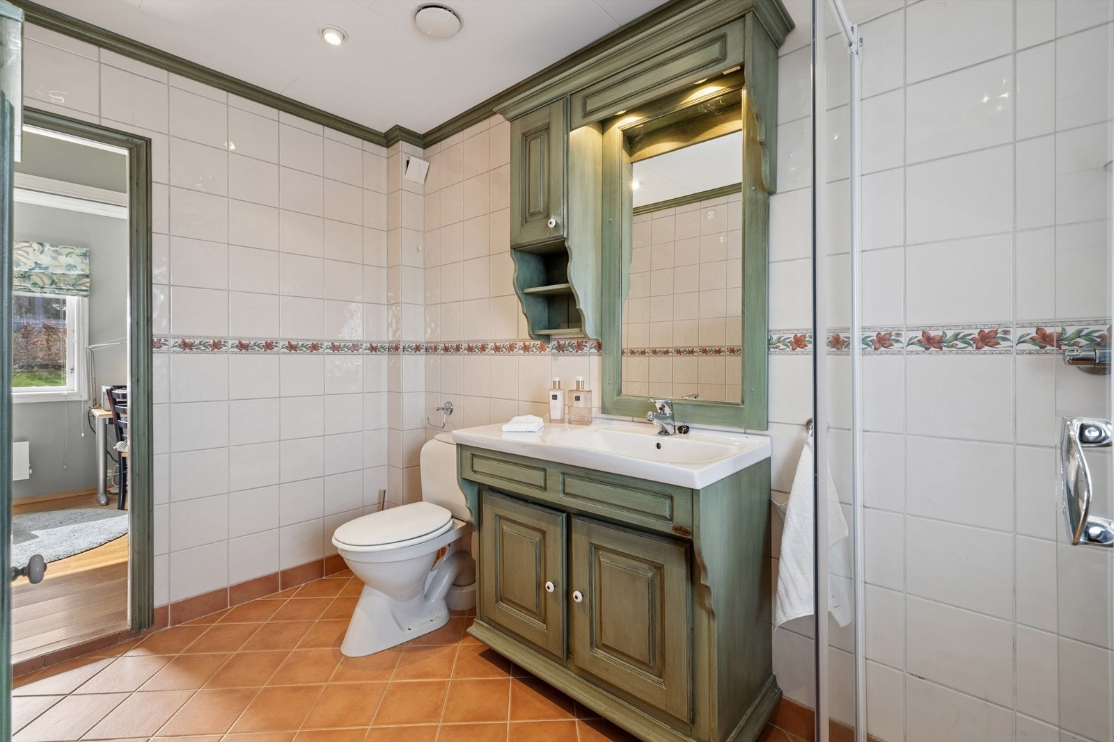 Badet i første etasje er romslig og utstyrt med servant i helstøpt plate, gulvstående toalett og dusjhjørne. Galleribilde