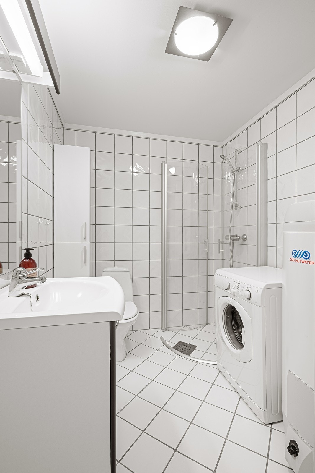 Bad med wc, dusjhjørne og håndvask med speil og skap. Opplegg for vaskemaskin. Galleribilde