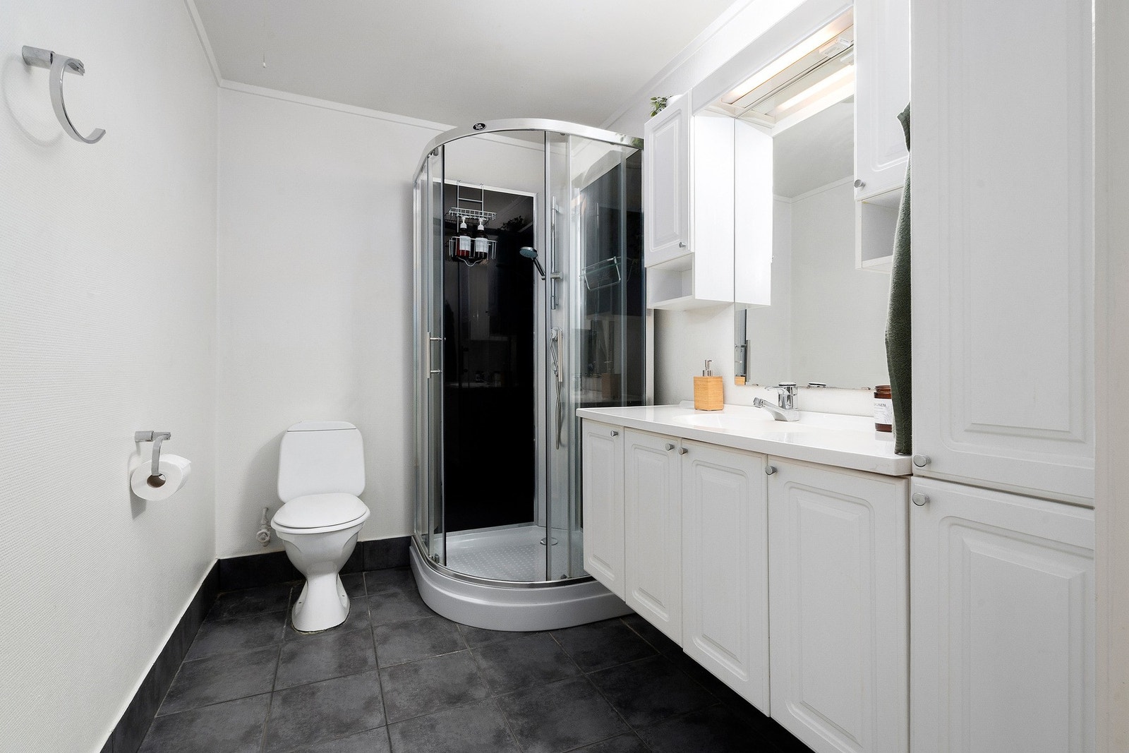 Badet er av god størrelse og er innredet med dusjkabinett, toalett og baderomsinnredning med servant og godt med oppbevaringsplass. Galleribilde
