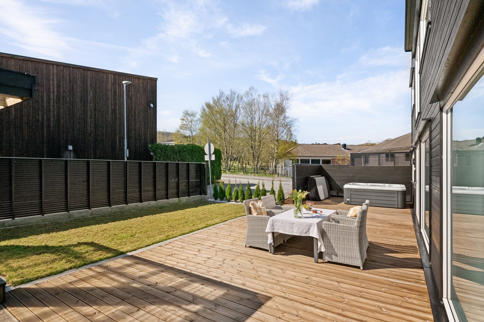 Tomten er pent opparbeidet med en kombinasjon av terrasse, plen og beplantning. Det er plantet Tujahekk mot parkeringsplass og tursti. Galleribilde