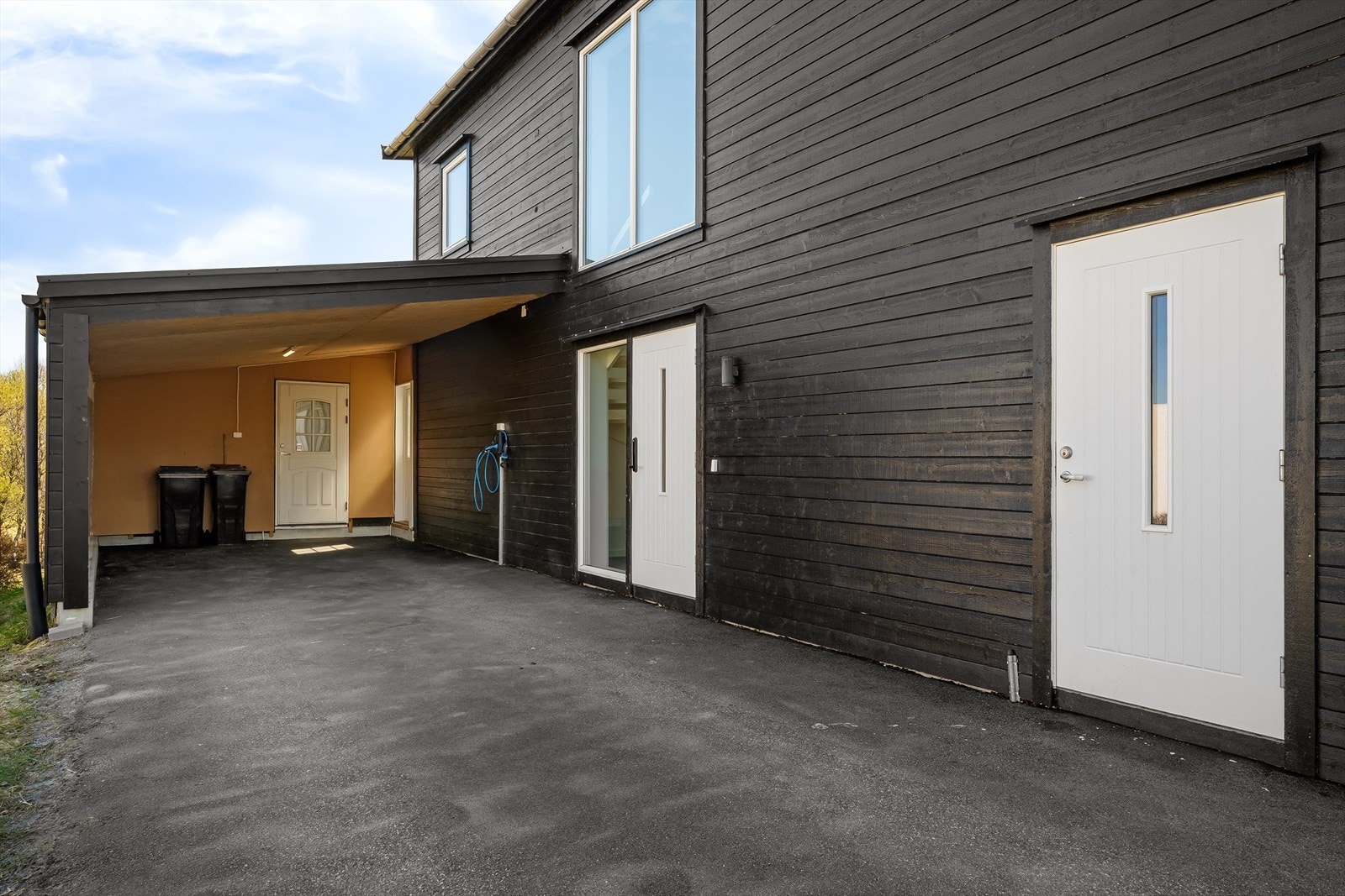 Integrert carport med elbil-lader, asfaltert dekke og direkte inngang til både bod og vaskerom legger opp til en praktisk og tørr hverdag. Galleribilde