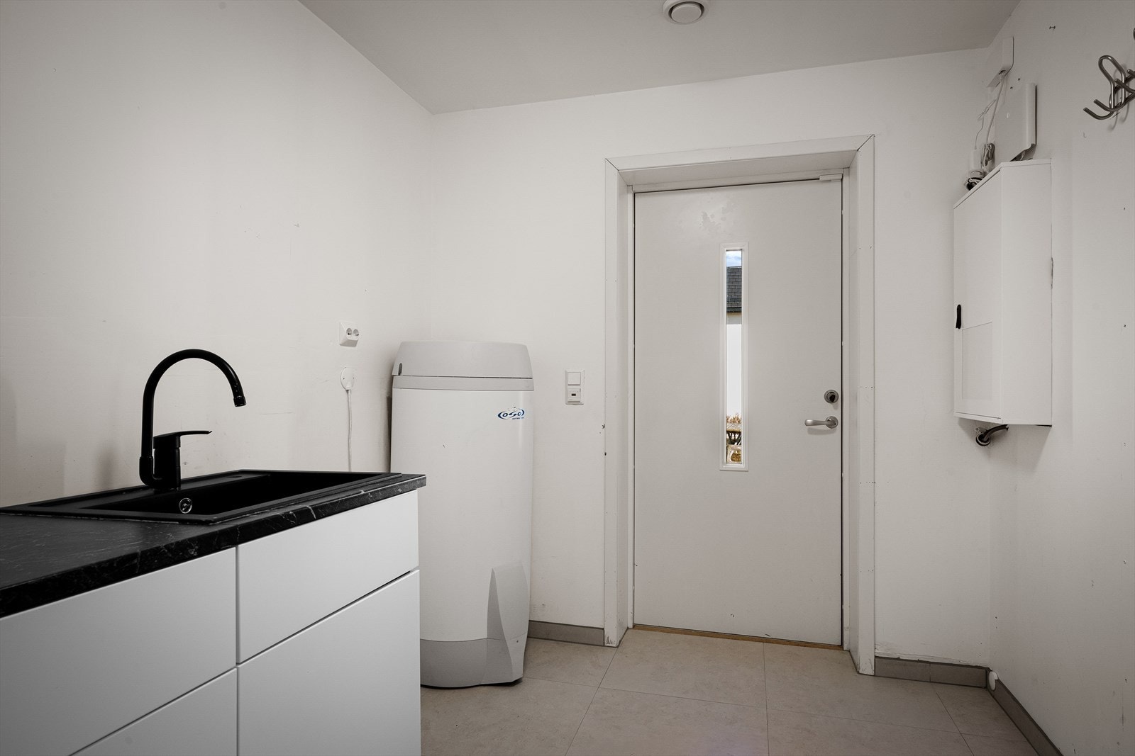 Separat vaskerom med flislagt gulv med varmekabler, opplegg for vaskemaskin og egen utgang. Gode lagringsmuligheter, og perfekt for tørking av våte regnklær. Galleribilde