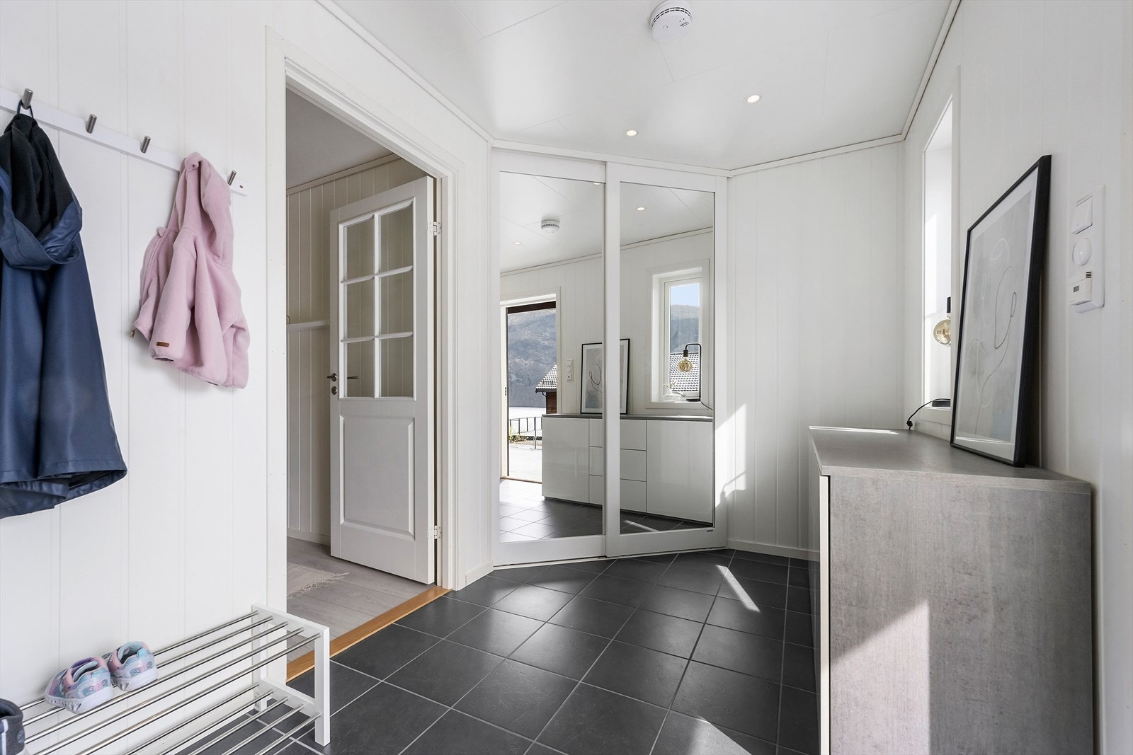 Entréen har flislagt golv med varmekablar og ein romsleg skyvedørsgarderobe med spegelfrontar Galleribilde
