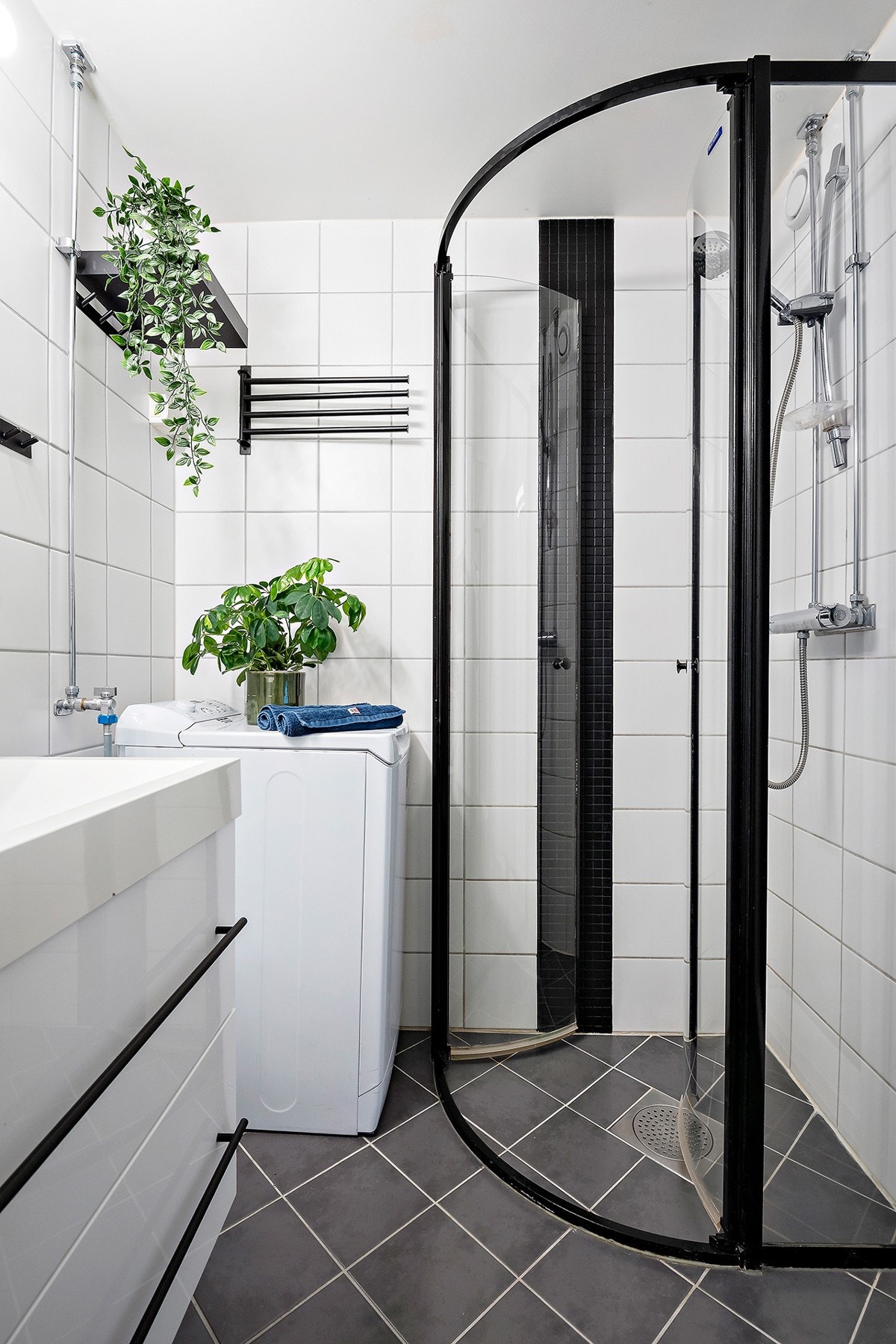 Badet er innredet med servant, veggspeil, opplegg for vaskemaskin, veggmontert toalett og dusjhjørne Galleribilde