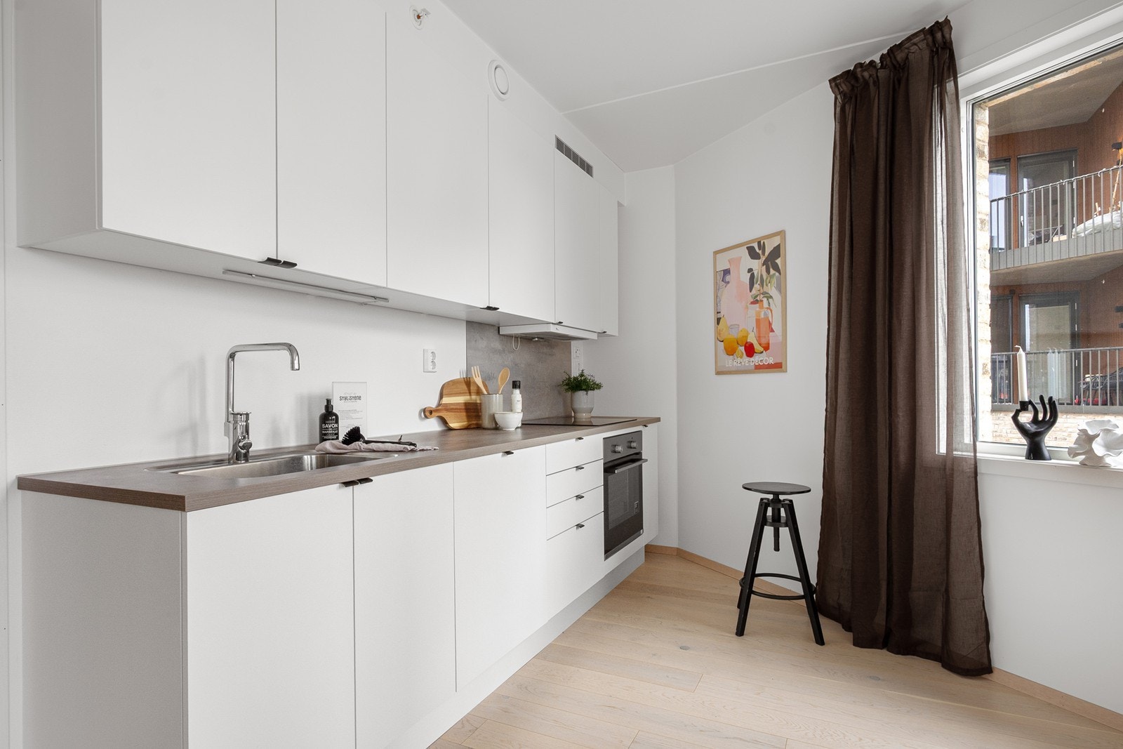 Kjøkkenet er plassert i hjørne og har god oppbevaringsplass i over- og underskap. Innredningen har slette, hvite fronter og laminat benkeplate med nedfelt kum. Galleribilde