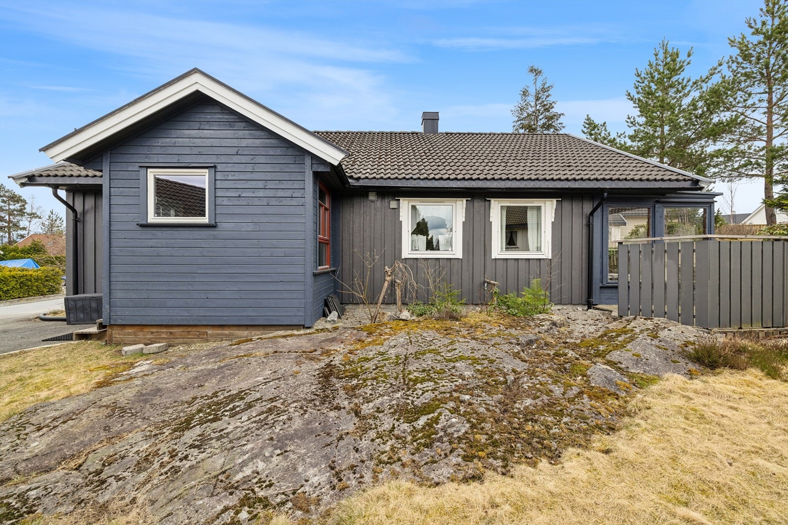 Eiendommen ligger på en lett skrånende tomt med en blanding av opparbeidet hage og synlig fjell. Galleribilde