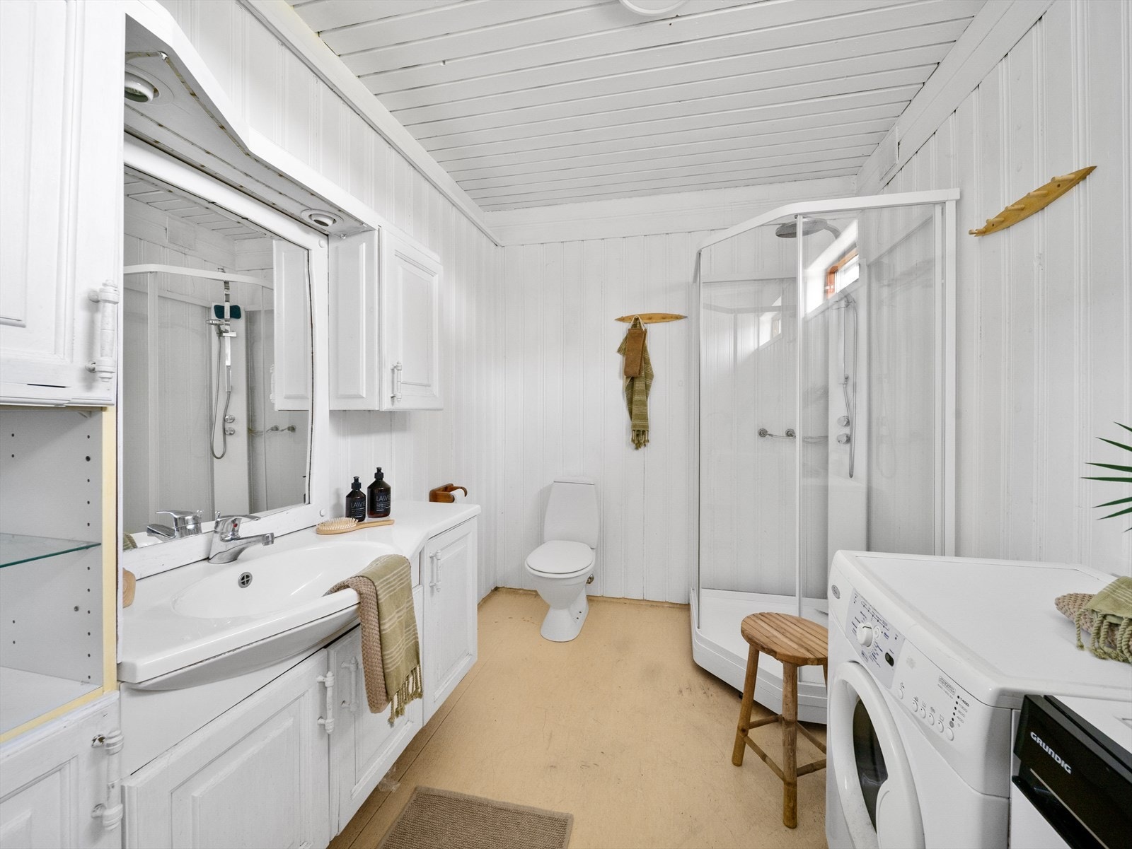 Badet i hybelen er innredet med baderomsmøbel med speil, skap, og servant. WC, dusjkabinett, samt opplegg for vaskemaskin og tørketrommel. Galleribilde