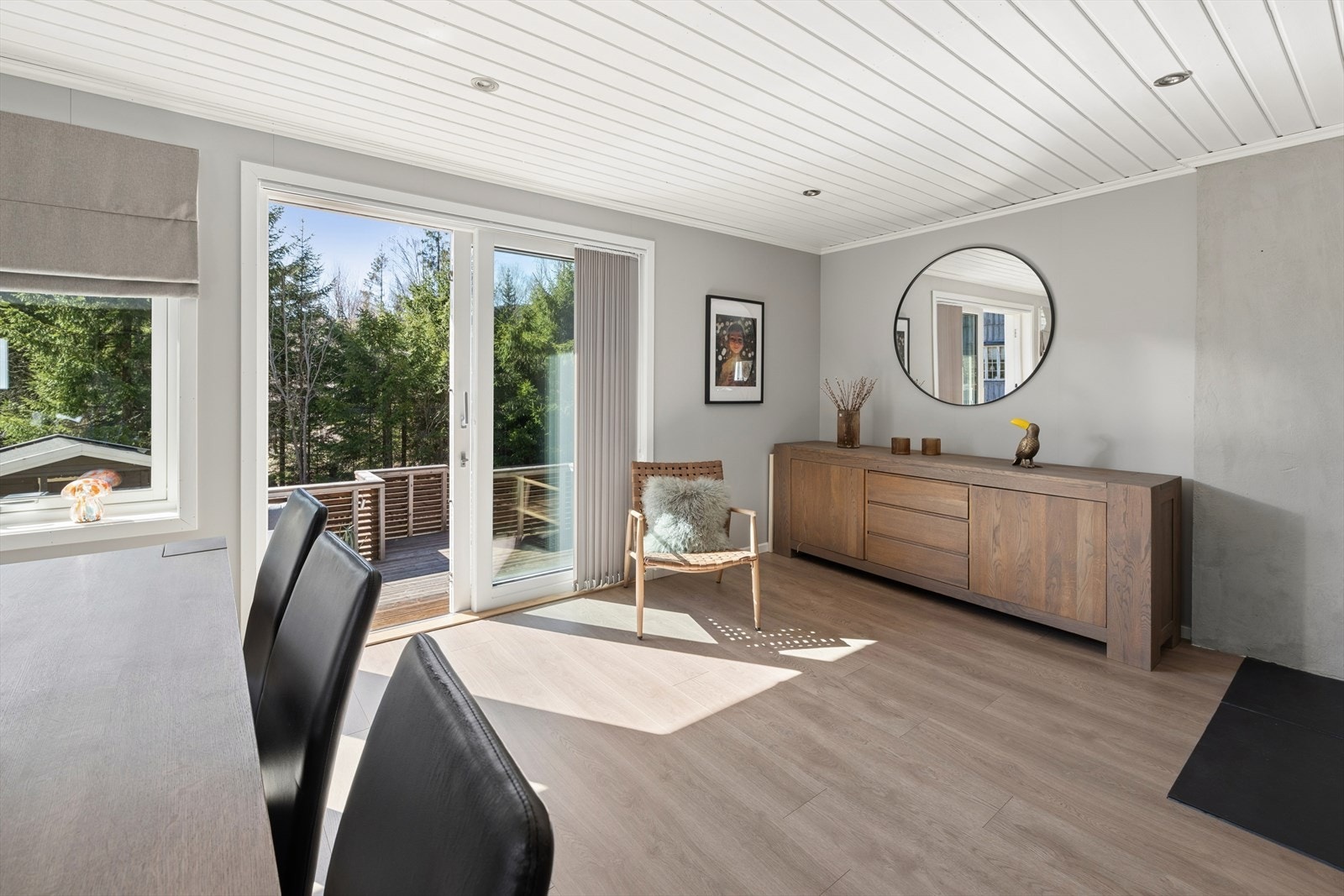 Det er store vinduer og skyvedør ut til veranda og hage. Galleribilde