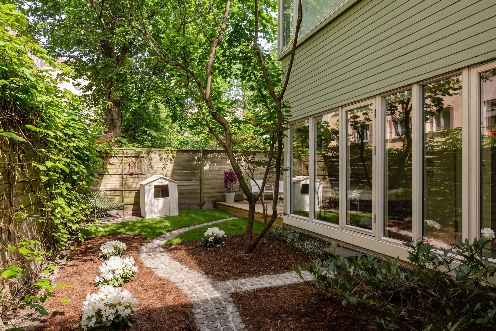 Her har du en nydelig bakhage som er pent opparbeidet med plen, beplanting og terrasse.
Vegetasjon i foto er redigert med AI, og det tas forbehold om eventuelle feil. Galleribilde
