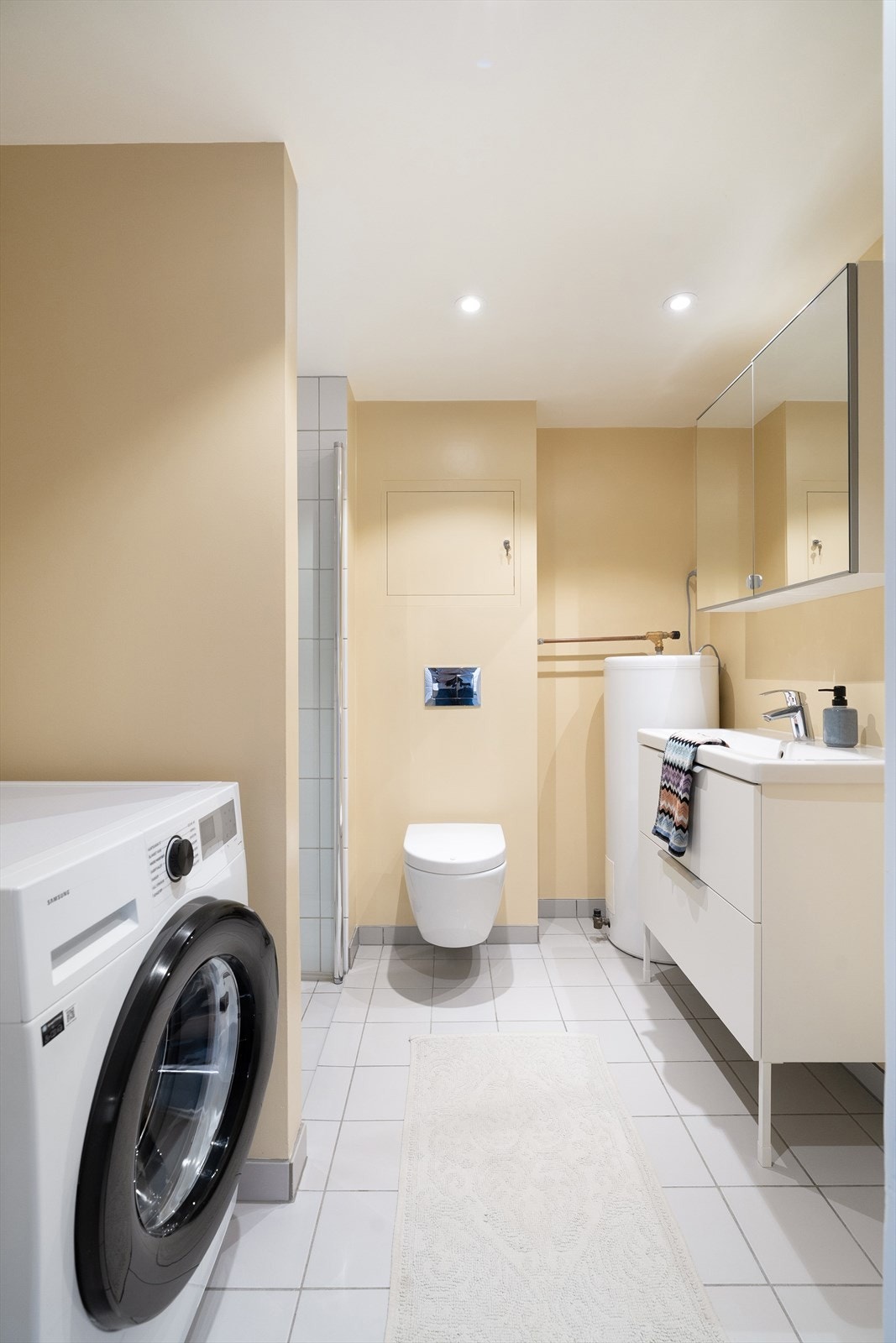 Badet er moderne innredet med vegghengt toalett, dusjnisje, hel servant og opplegg til vaskemaskin. Galleribilde