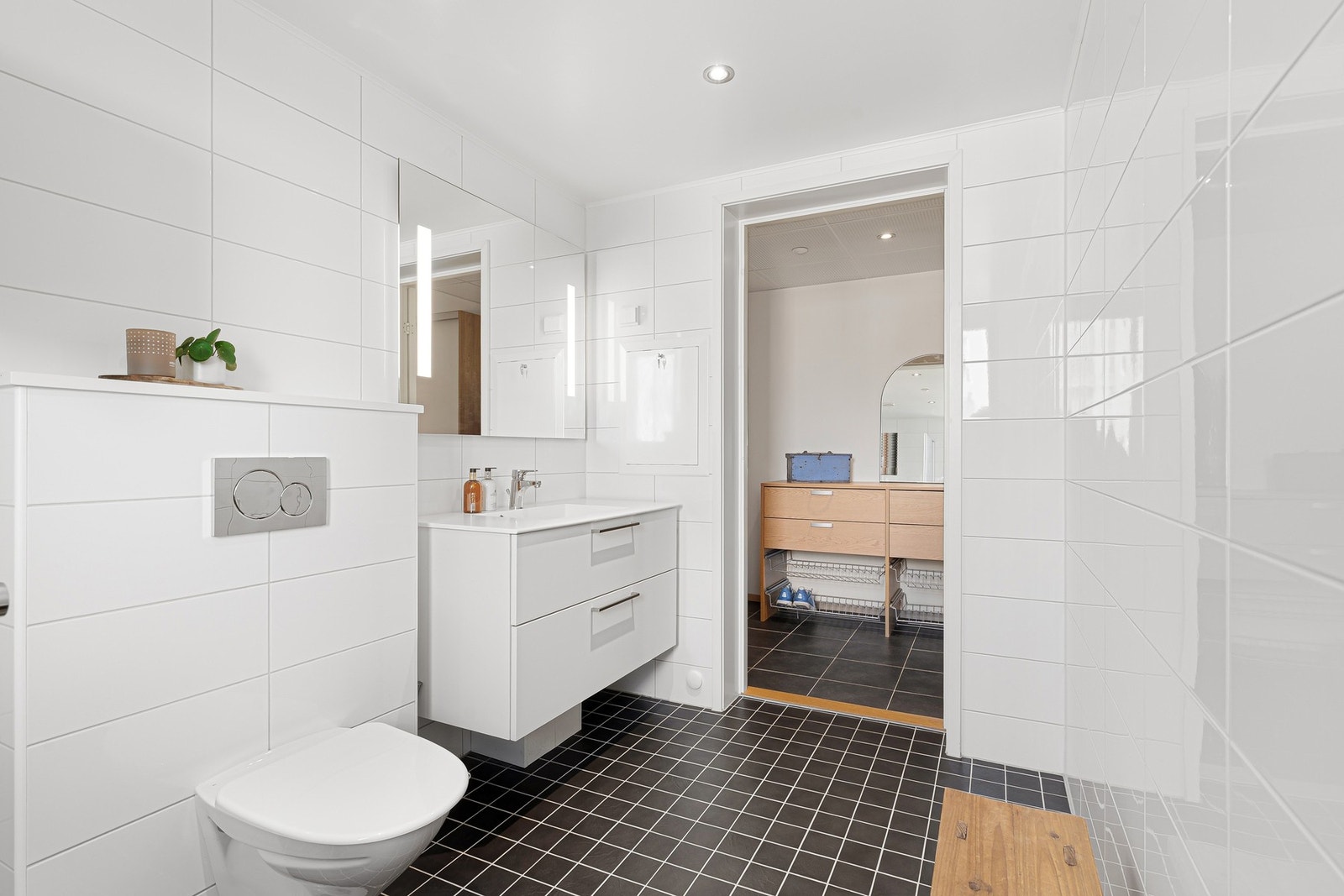 Badet nærmest entreen måler 5,8 kvm og er innredet med dusjhørne med innfellbare dusjdører i glass, vegghengt WC, servant på underskap, og speil, med elektriske varmekabler i gulv. Galleribilde