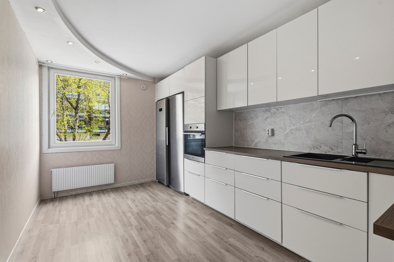 Kjøkkenet har en praktisk innredning med glatte fronter og benkeplate i slitesterk laminat Galleribilde