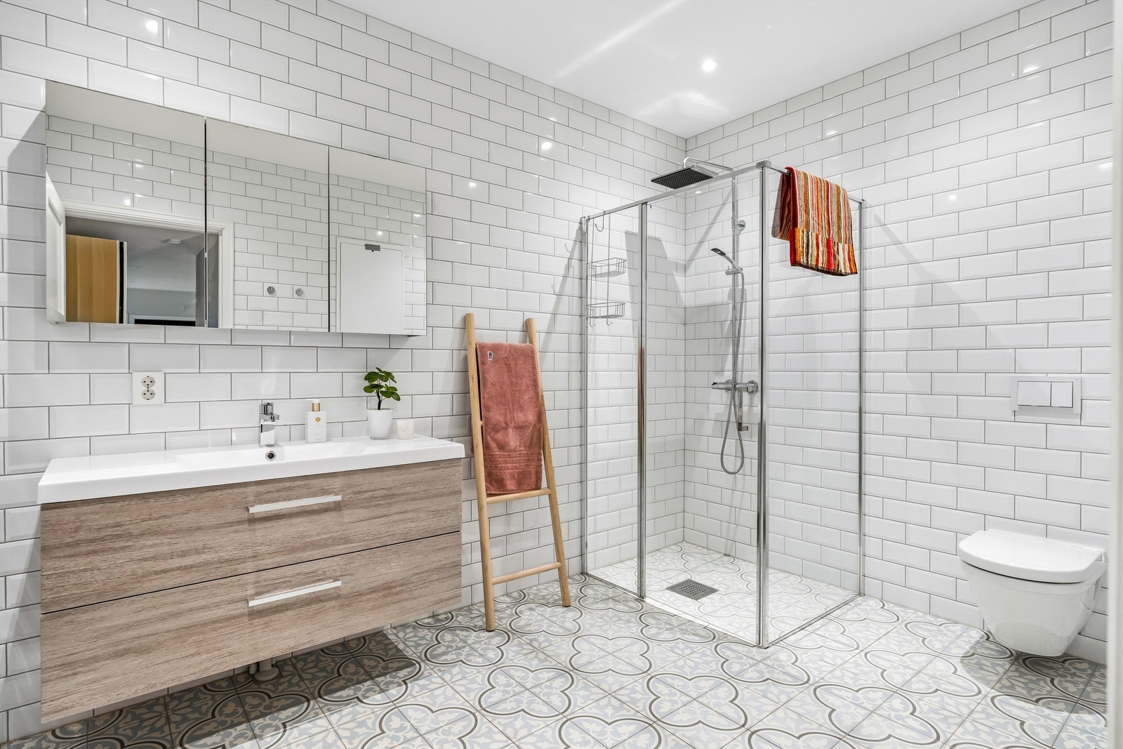 I første etasje har badet god størrelse, innredet med hvite på veggene og lyse gulvfliser i et lekkert mønster. På badet er det downlights, varmekabler og vegghengt toalett. Galleribilde