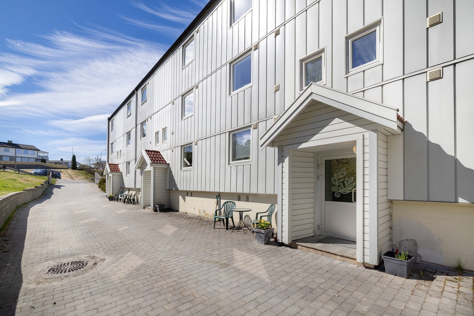 Adkomst til leiligheten via felles trappeoppgang. Tomten er opparbeidet med belegningsstein ved inngangspartiene. Galleribilde