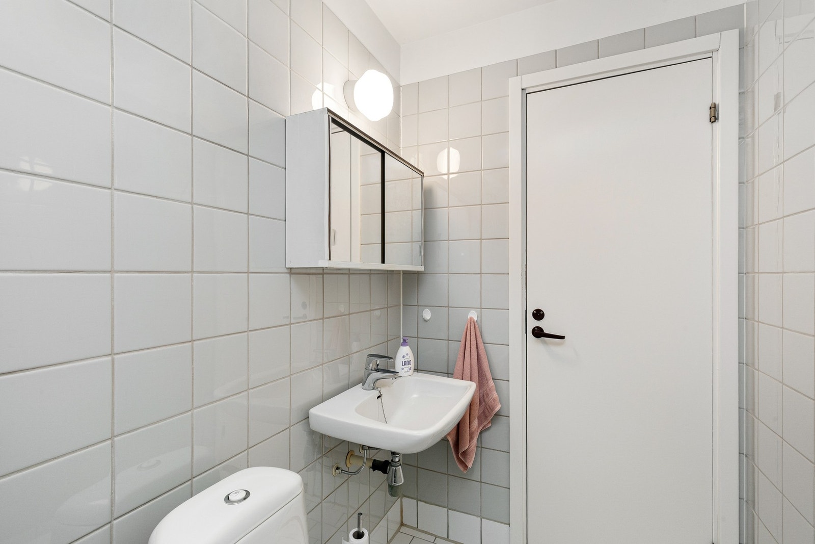 Badet er utstyrt med vegghengt servant og speilskap, dusjhjørne og gulvstående toalett. Galleribilde