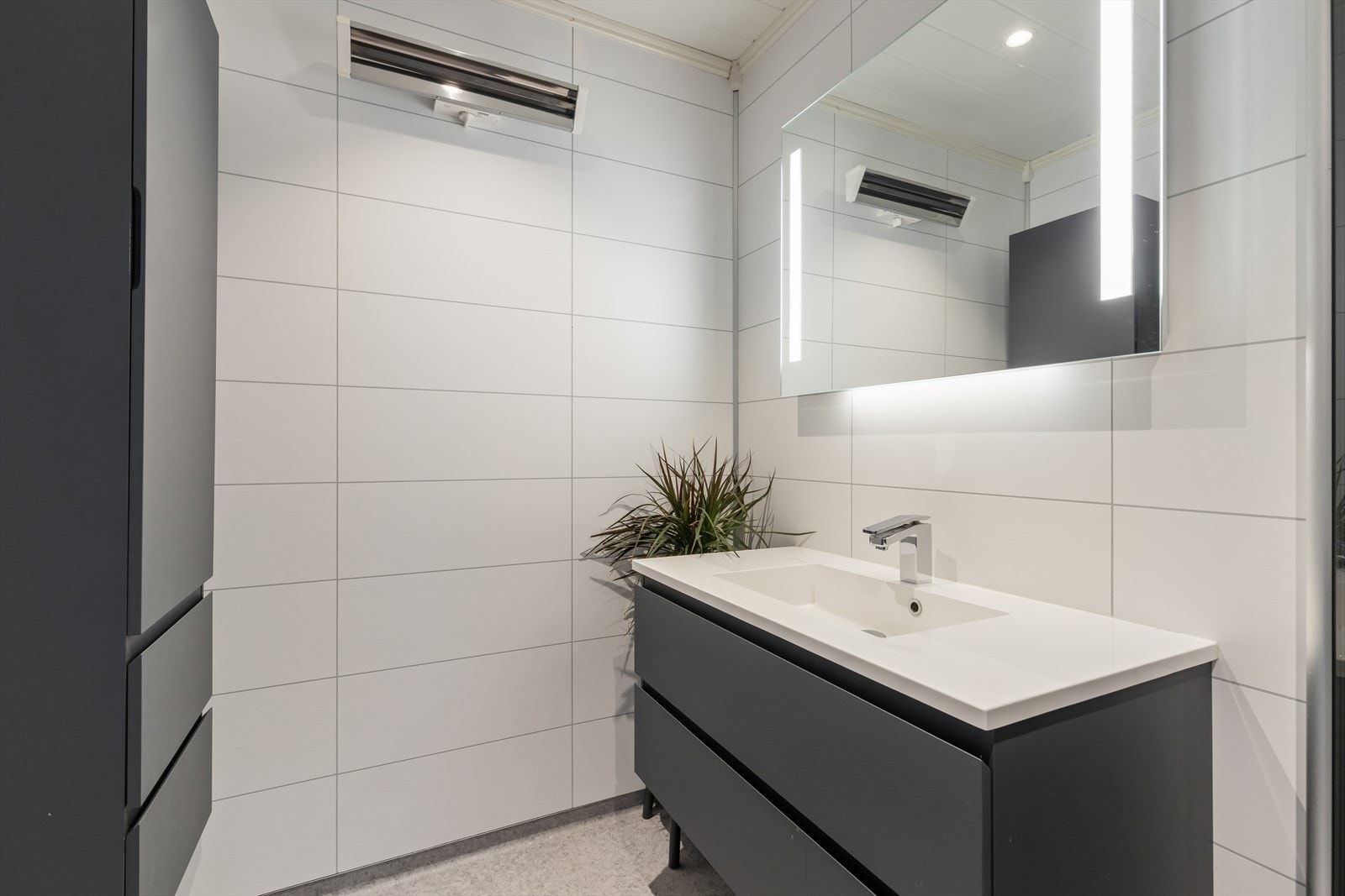 Badet er utstyrt med veggskap, baderomsinnredning med servant og speil, samt dusjhjørne med innfellbare vegger. Galleribilde
