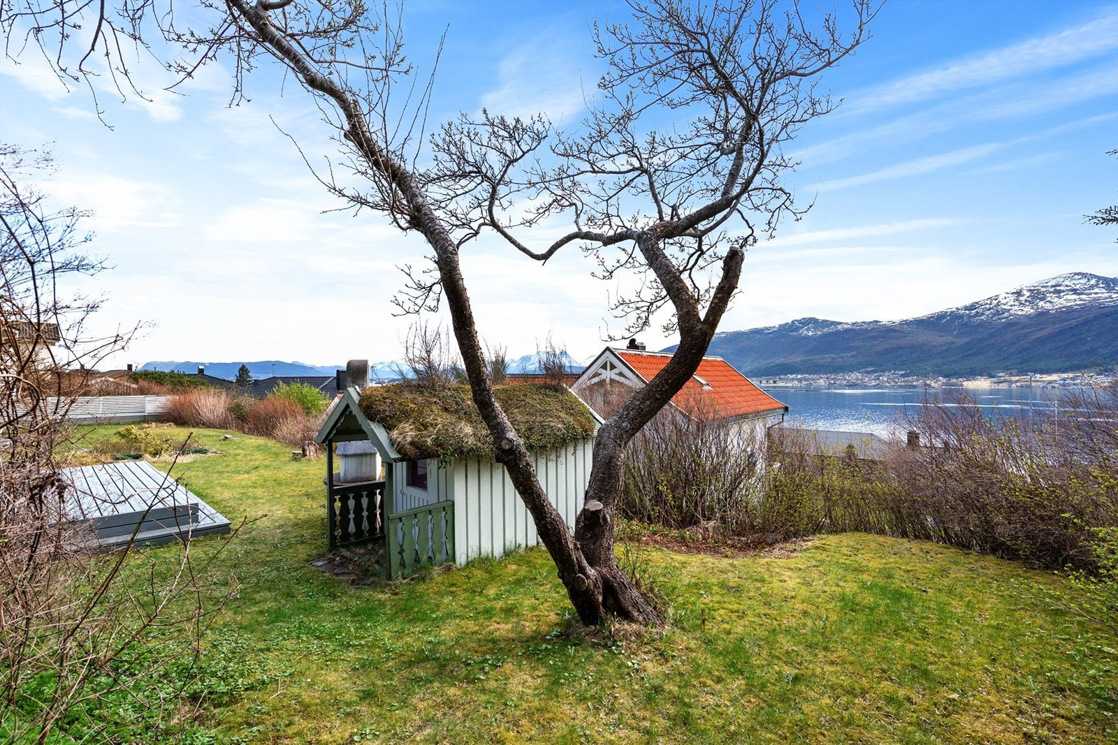 I hagen står et sjarmerende uthus på ca. 7 m² med torvtak. Foran uthuset er det en terrasseplatting på ca. 16 m². Galleribilde