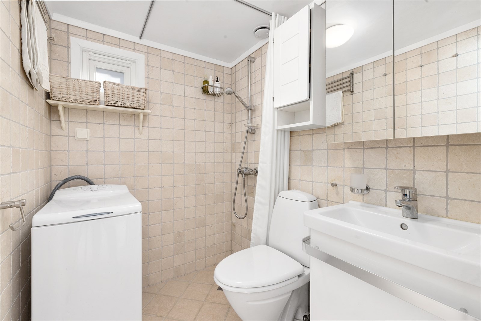 Pent bad fra 2009 med flislagte overfl ater og elektrisk gulvvarme. Badet er innredet med nytt dusjkabinett etter bildet ble tatt og servantskap med glatte fronter, overlimt servant, speilskap med lys og veggskap. Opplegg for vaskemaskin. Galleribilde