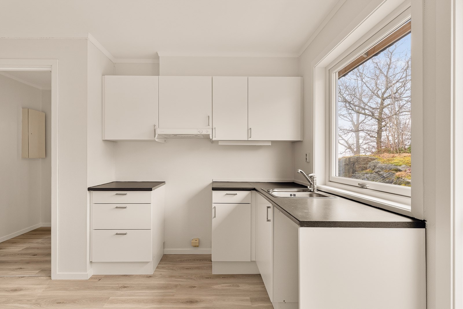 Kjøkkeninnredning med glatte fronter, laminat benkeplate og kjøkkenventilator med avtrekk ut. Galleribilde