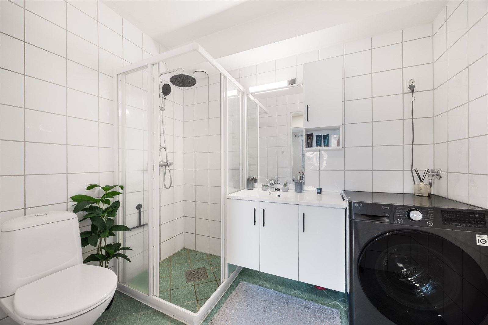 Pent, flislagt baderom med elektriske varmekabler i gulv, gulvmontert toalett og dusjkabinett. Veggmontert servantskap med heldekkende servantplate, samt speil, sideskap og overlys med el-stikk på vegg. Galleribilde