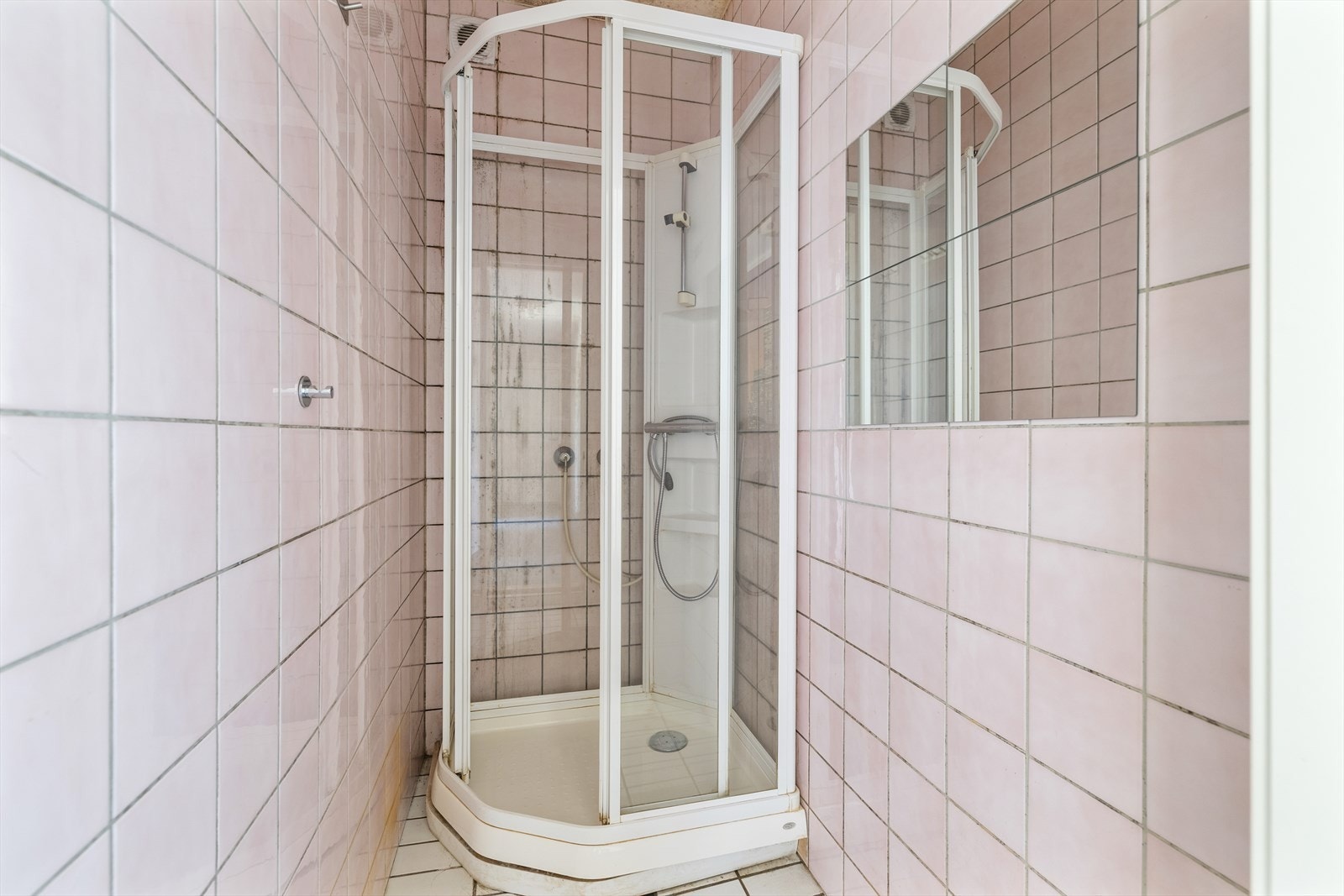 Badet er flislagt, og er innredet med dusjkabinett og speil. Galleribilde