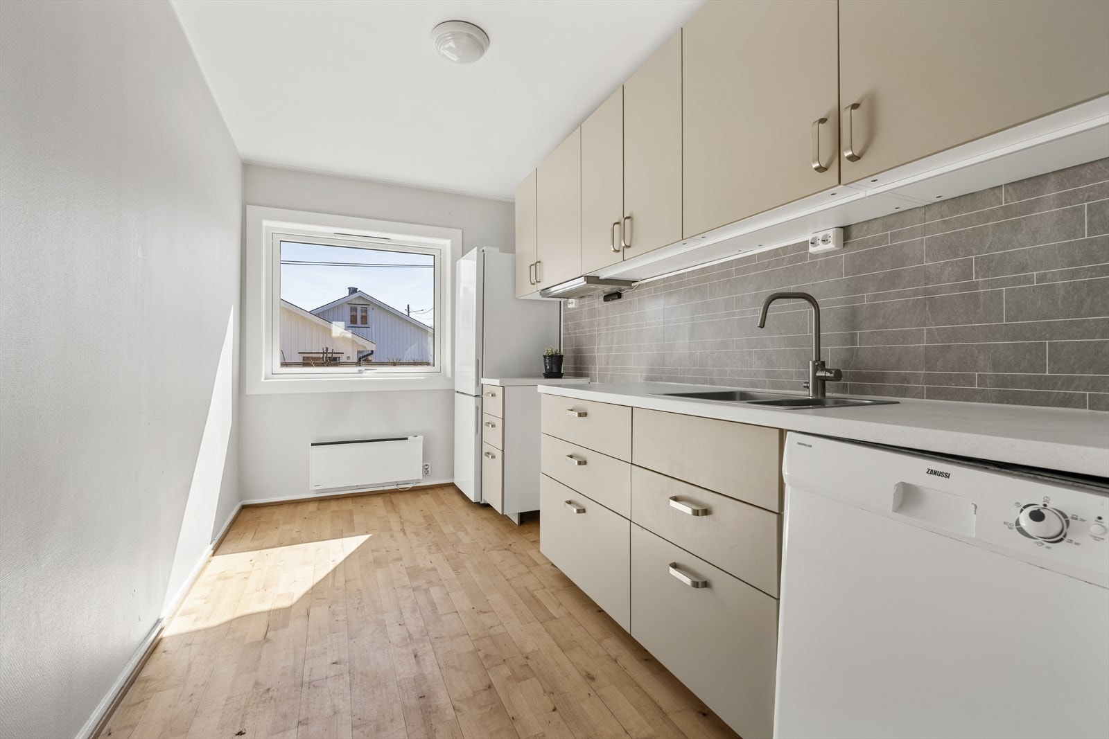 Kjøkkenet ligger i et eget rom og har innredning med lyse fronter og laminert benkeplate med dobbel oppvaskkum. Galleribilde